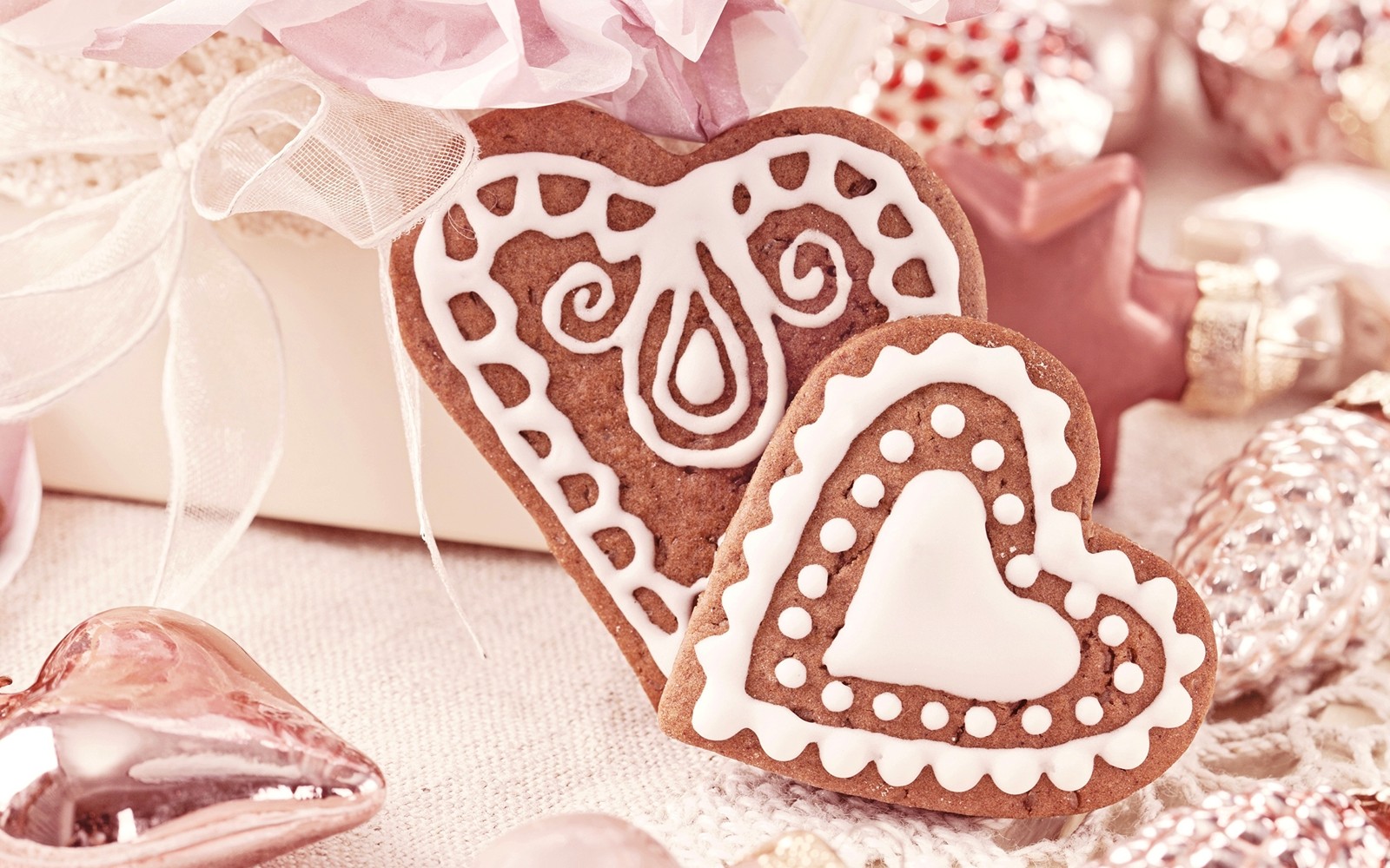 Hay dos galletas en forma de corazón sobre una mesa con otras decoraciones (corazón, postre, galleta, pan de jengibre, glaseado)