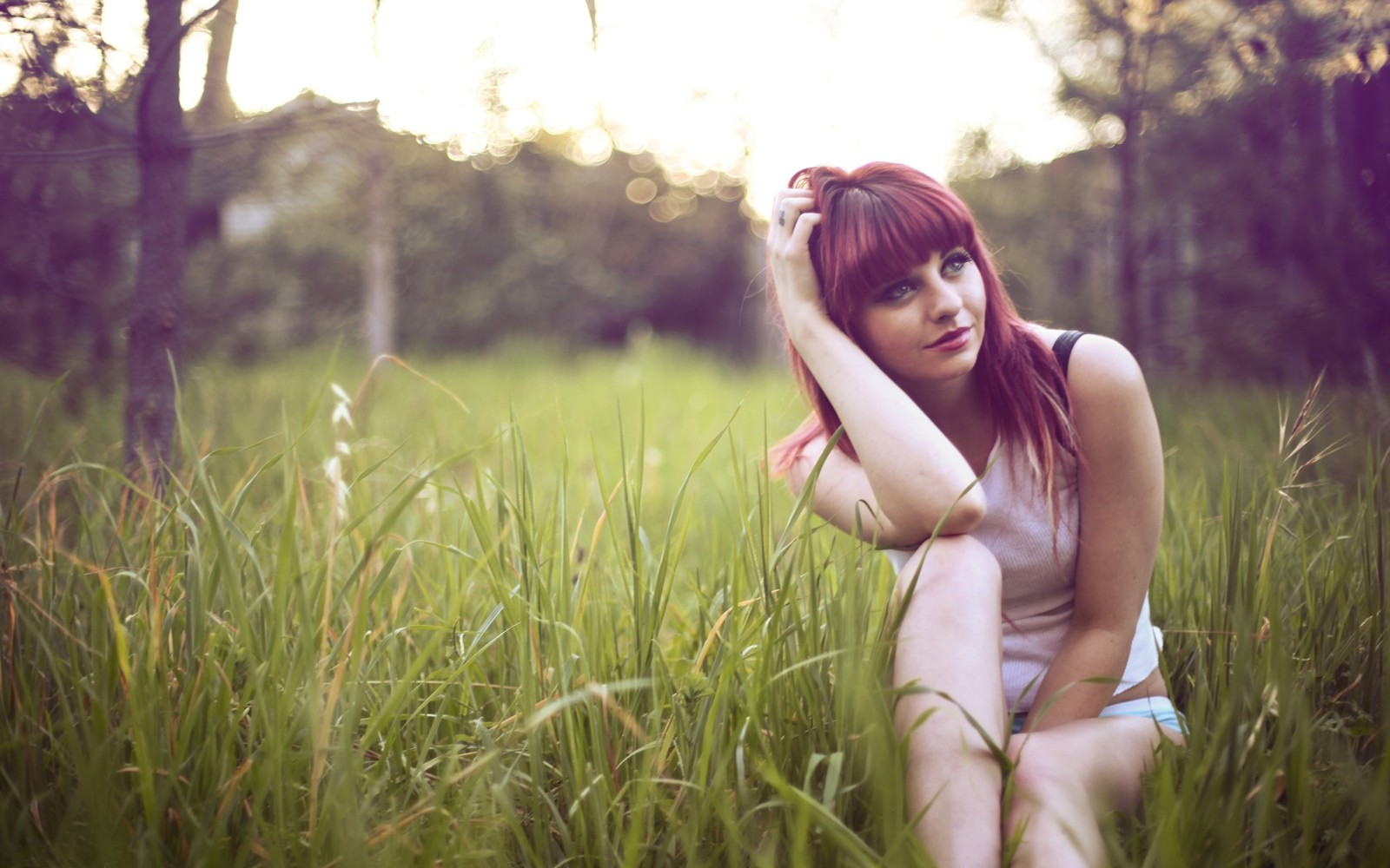 Une femme est assise dans un champ d'herbe haute (nature, beauté, ensoleillement, lumière, photographie de portrait)