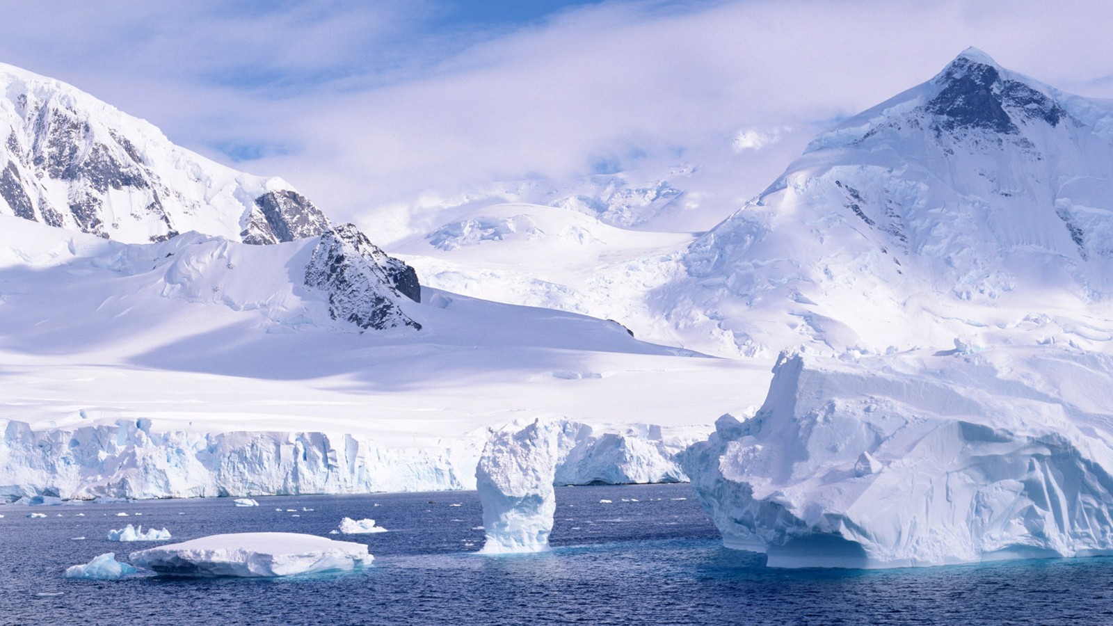 Montañas cubiertas de nieve y hielo con un bote en el agua (nieve, montaña, casquete polar, hielo, iceberg)