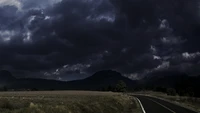 Camino montañoso tormentoso bajo nubes cúmulo oscuras