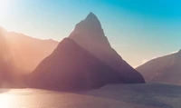 Majestoso Pico Mitre ao amanhecer, Milford Sound, Nova Zelândia, banhado pela luz da manhã com um céu azul claro.