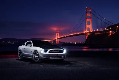 Eleganter Shelby Mustang, der nachts mit der beleuchteten Golden Gate Bridge im Hintergrund geparkt ist.