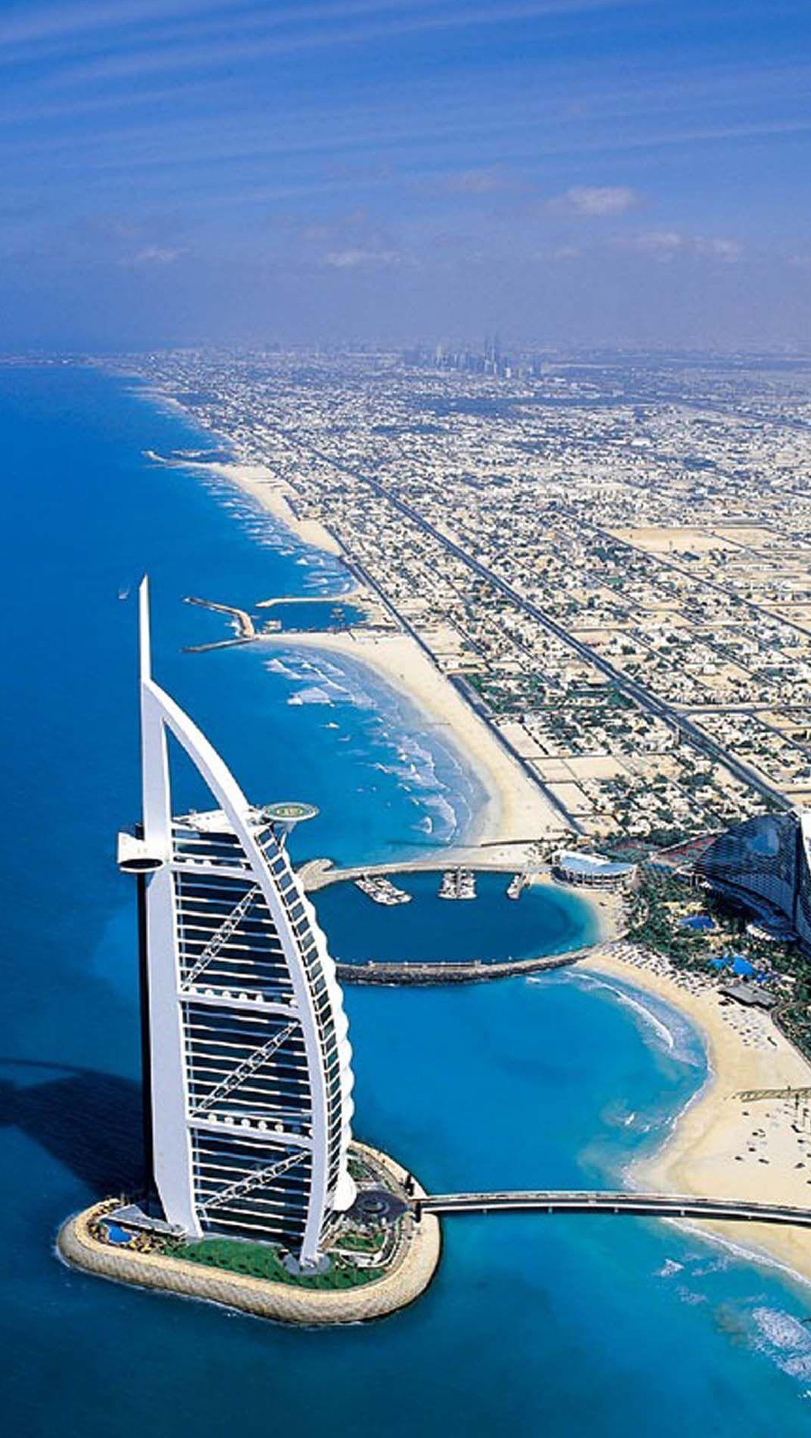 Vista aérea de uma praia e uma cidade com um prédio alto (dubai, relaxamento, viagem)