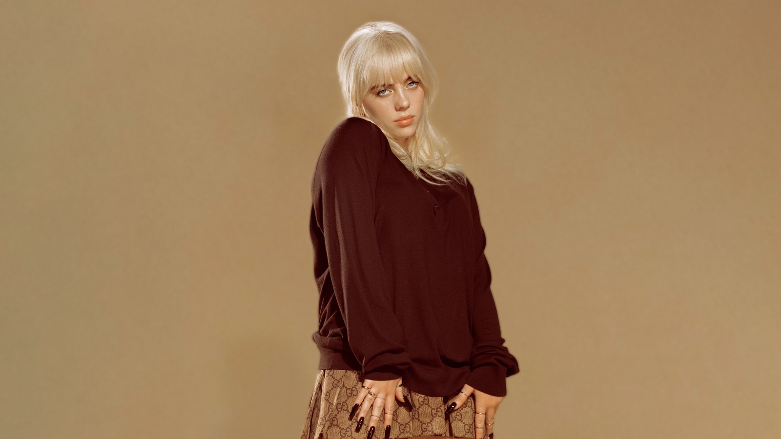 Femme blonde en pull marron et jupe à motifs posant pour une photo (plus heureux que jamais, billie eilish, 8k, beige, 5k)