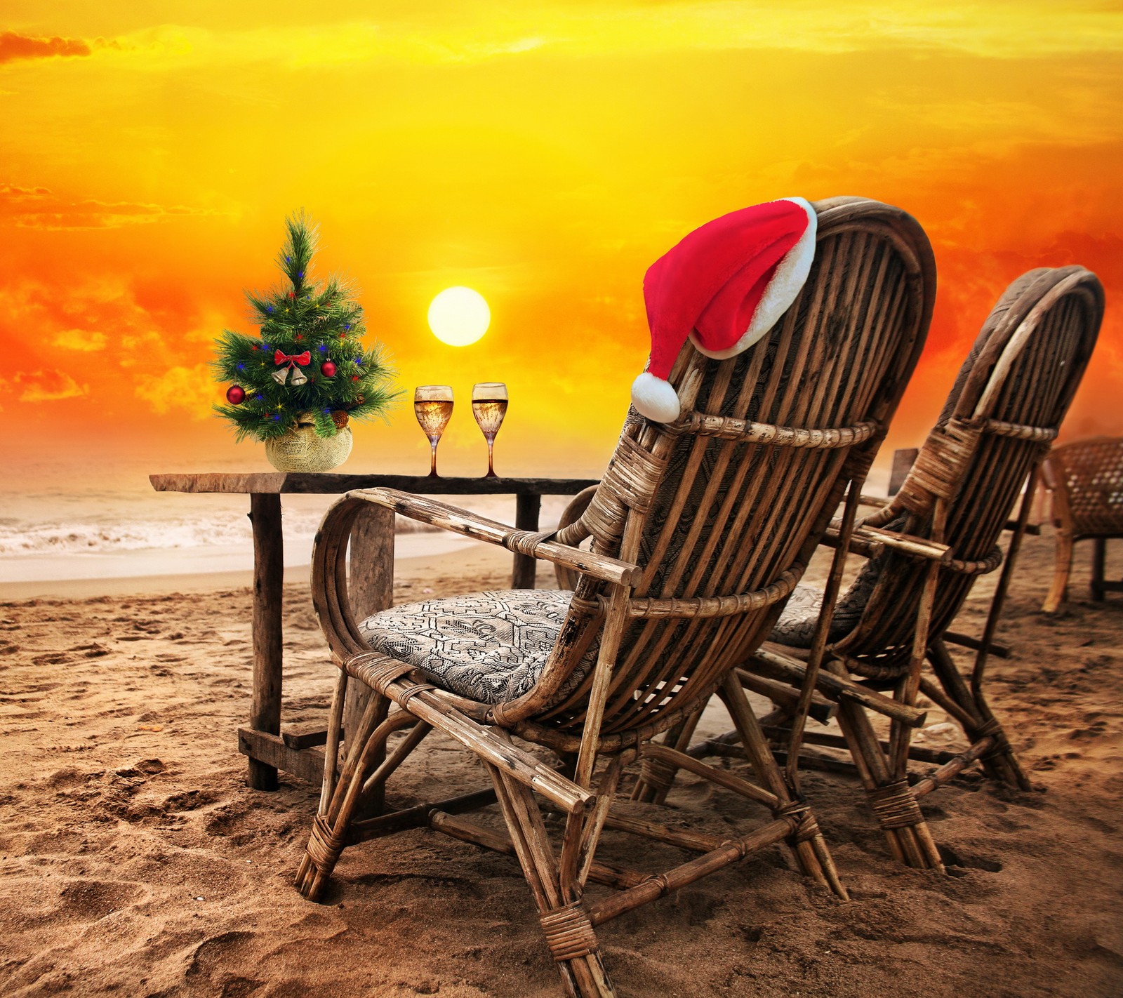 Arabischer stuhl mit weihnachtsmütze am strand mit einem weihnachtsbaum (strand, champagner, weihnachten, feiertag, sonnenuntergang)