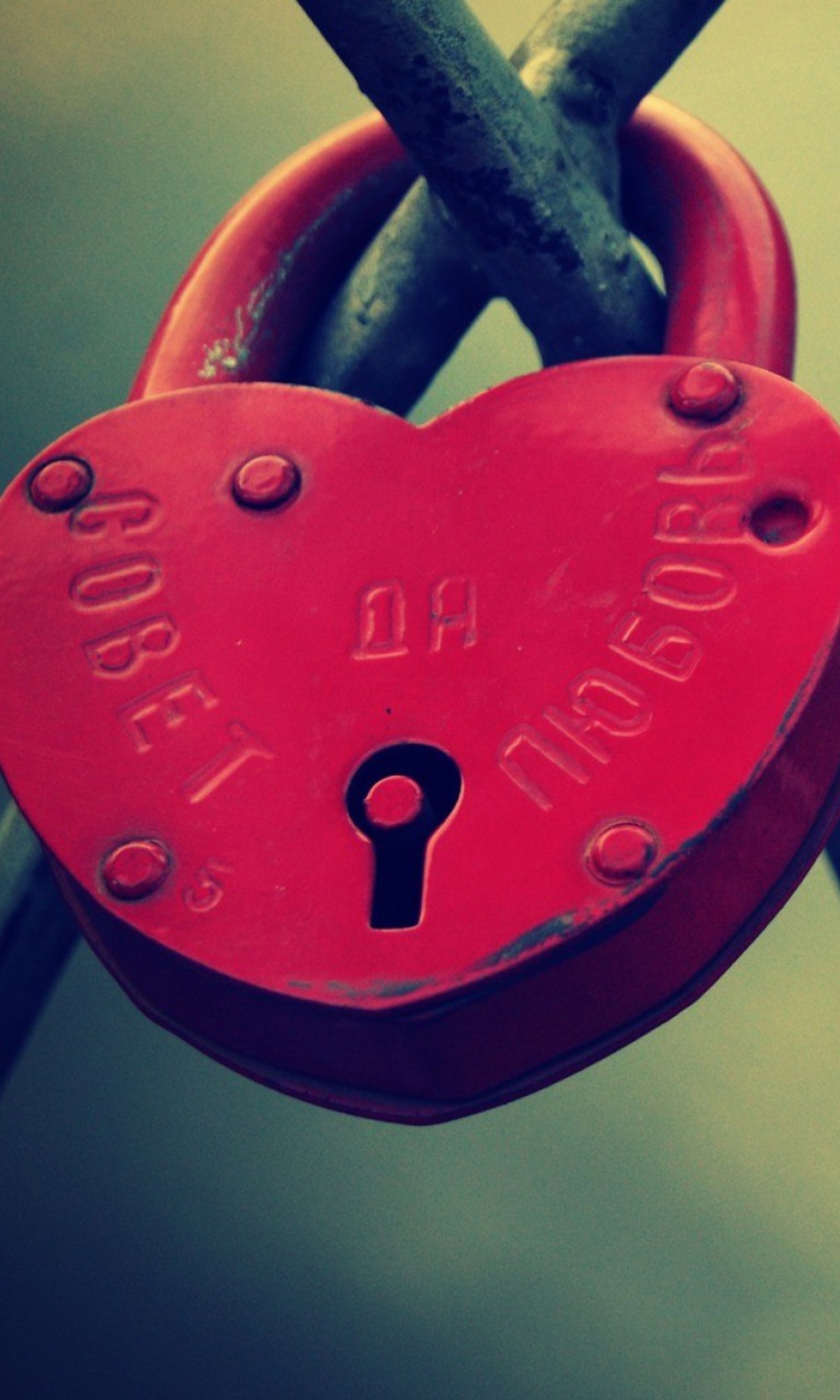 Un cadenas en forme de cœur rouge attaché à une clôture (cœur, amour)