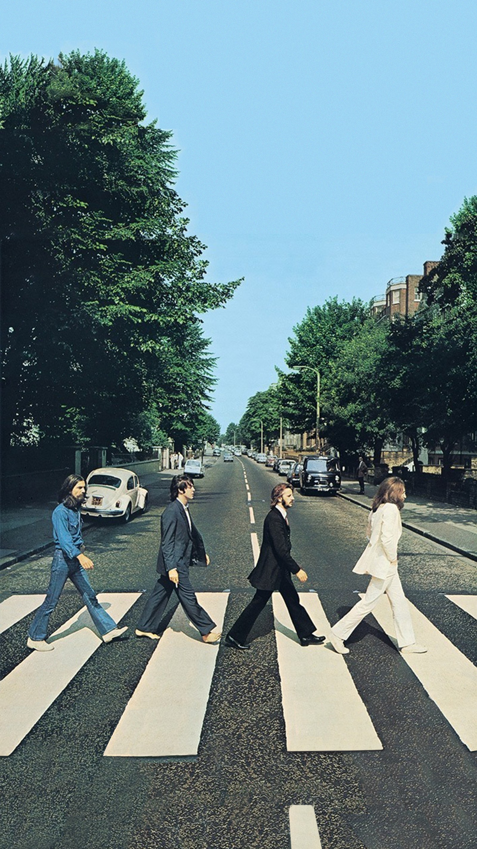 Araffe crossing the road in a crosswalk with a group of people (abbey road, beatles, here comes the sun, the beatles)