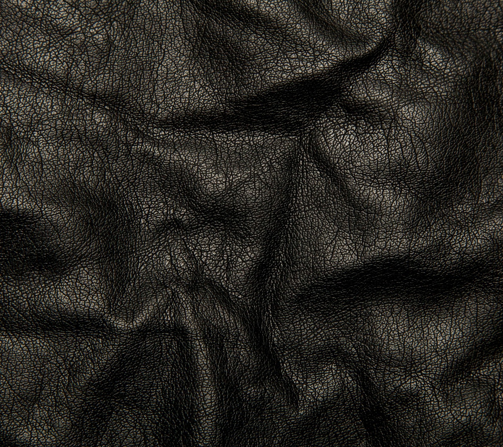 A close up of a black leather texture with a slight pattern (cracks, leather, wrinkles)