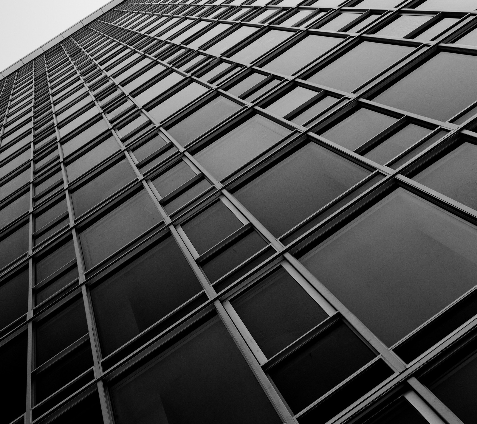 Arafed view of a tall building with many windows and a clock (black and white, building, glass, hd, tower)