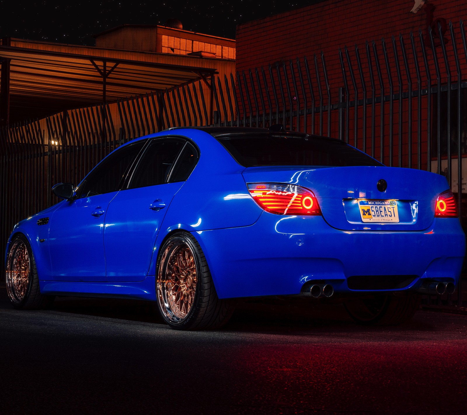 A close up of a blue car parked in front of a building (auto, bimmer, bmw, car, m5)