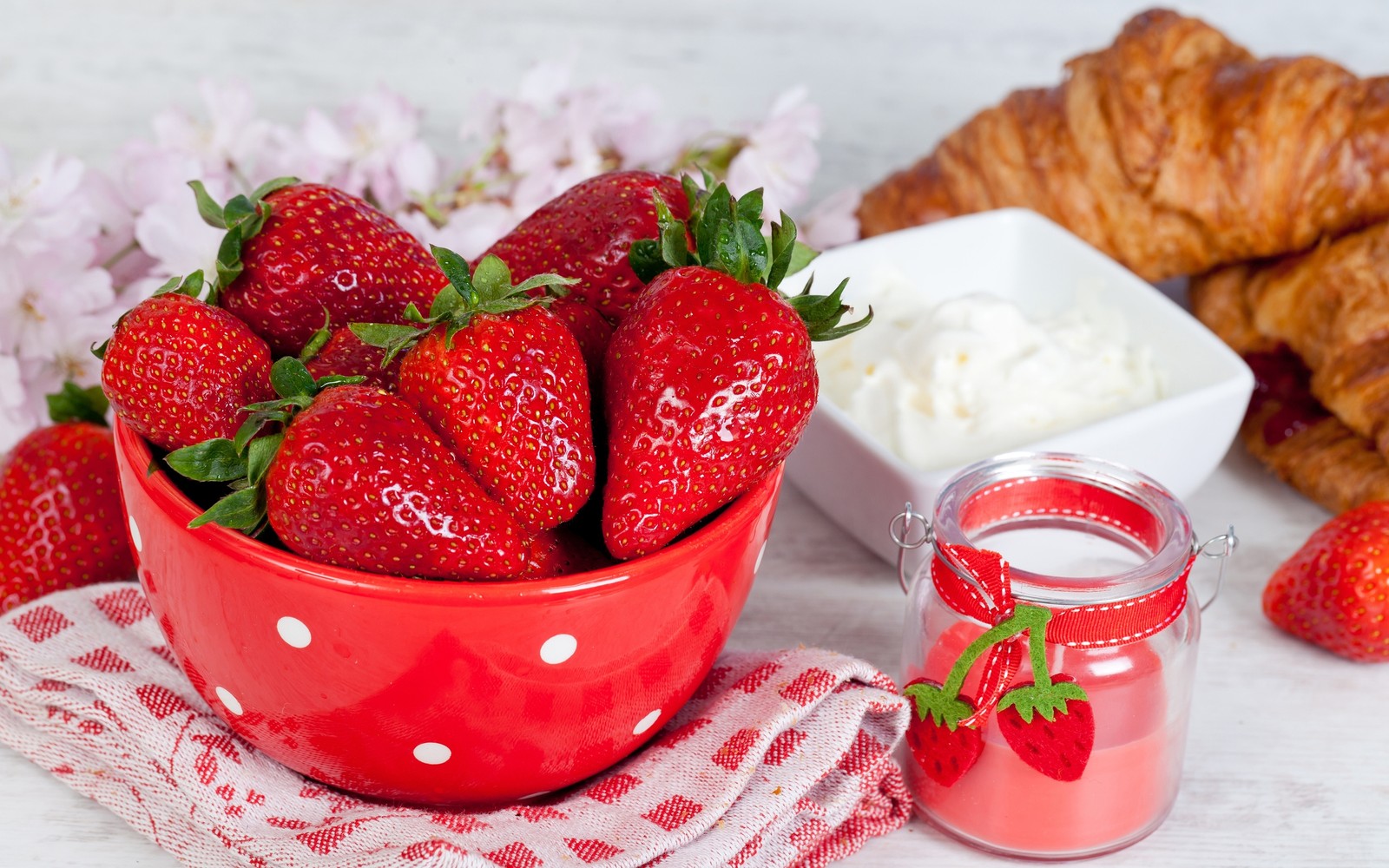 Uma tigela de morangos e croissants em uma mesa (morango, baga, fruta, sundae, comida)