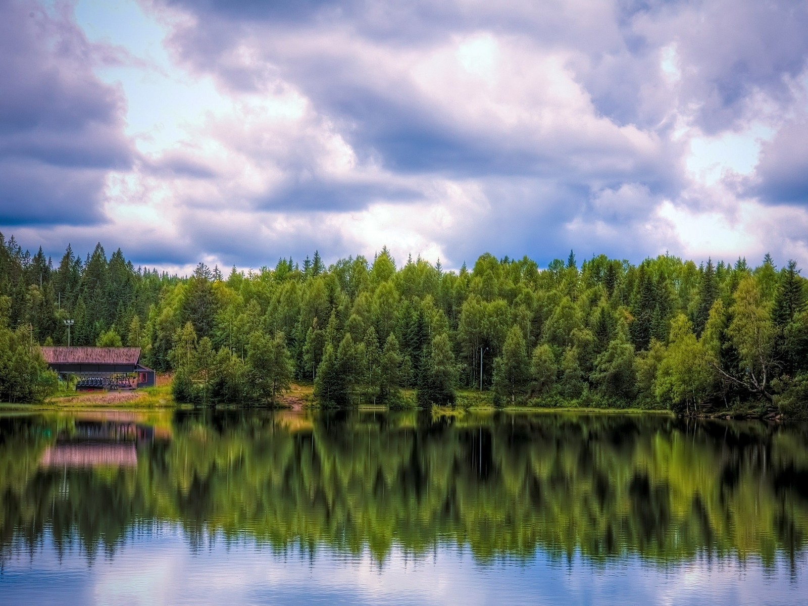 Há árvores refletidas na água de um lago com uma cabana ao fundo (reflexo, natureza, água, ecossistema, floresta)