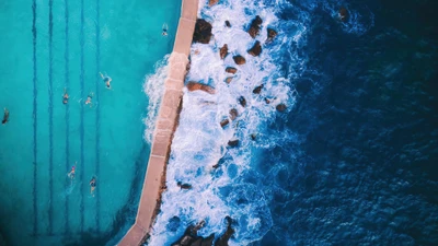 Vista aérea de nadadores en una piscina que se fusiona con el océano en Sídney, Australia