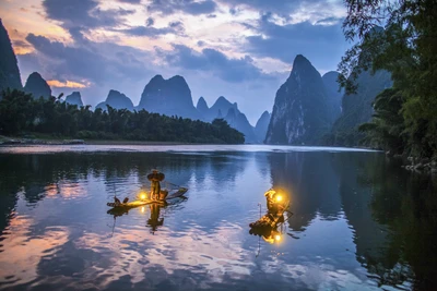 Serene Evening on the River: Fishermen with Lanterns Amidst Majestic Mountains