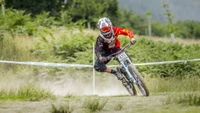 Ciclista de montaña de descenso dinámico compitiendo a través de un terreno accidentado, mostrando habilidad y velocidad en un deporte emocionante.