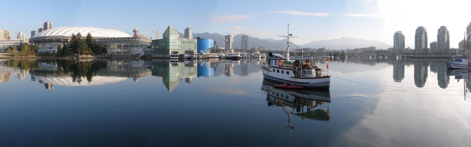 Um barco árabe na água com uma cidade ao fundo (transporte aquático, reflexo, barco, marina, porto)