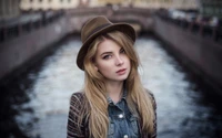 Winter Elegance: A Model with Long Brown Hair in a Hat by the River