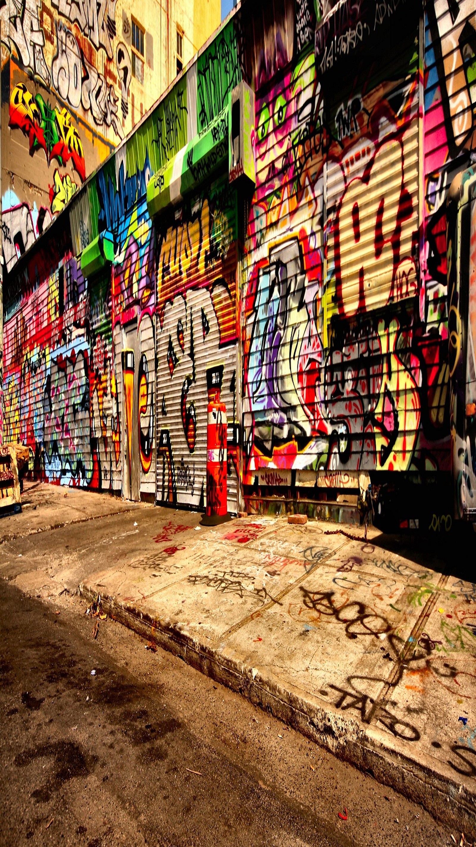 Una pared cubierta de graffiti en un callejón de la ciudad con un hidrante de incendios. (1089x1920, fondo de pantalla)