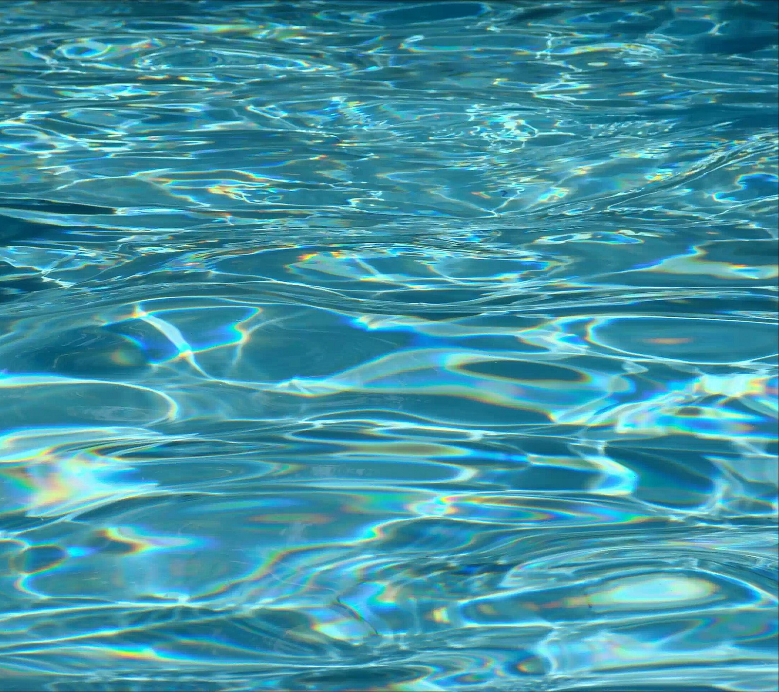 There is a pool with a blue water surface and a frisbee in it (blue, water, waves)