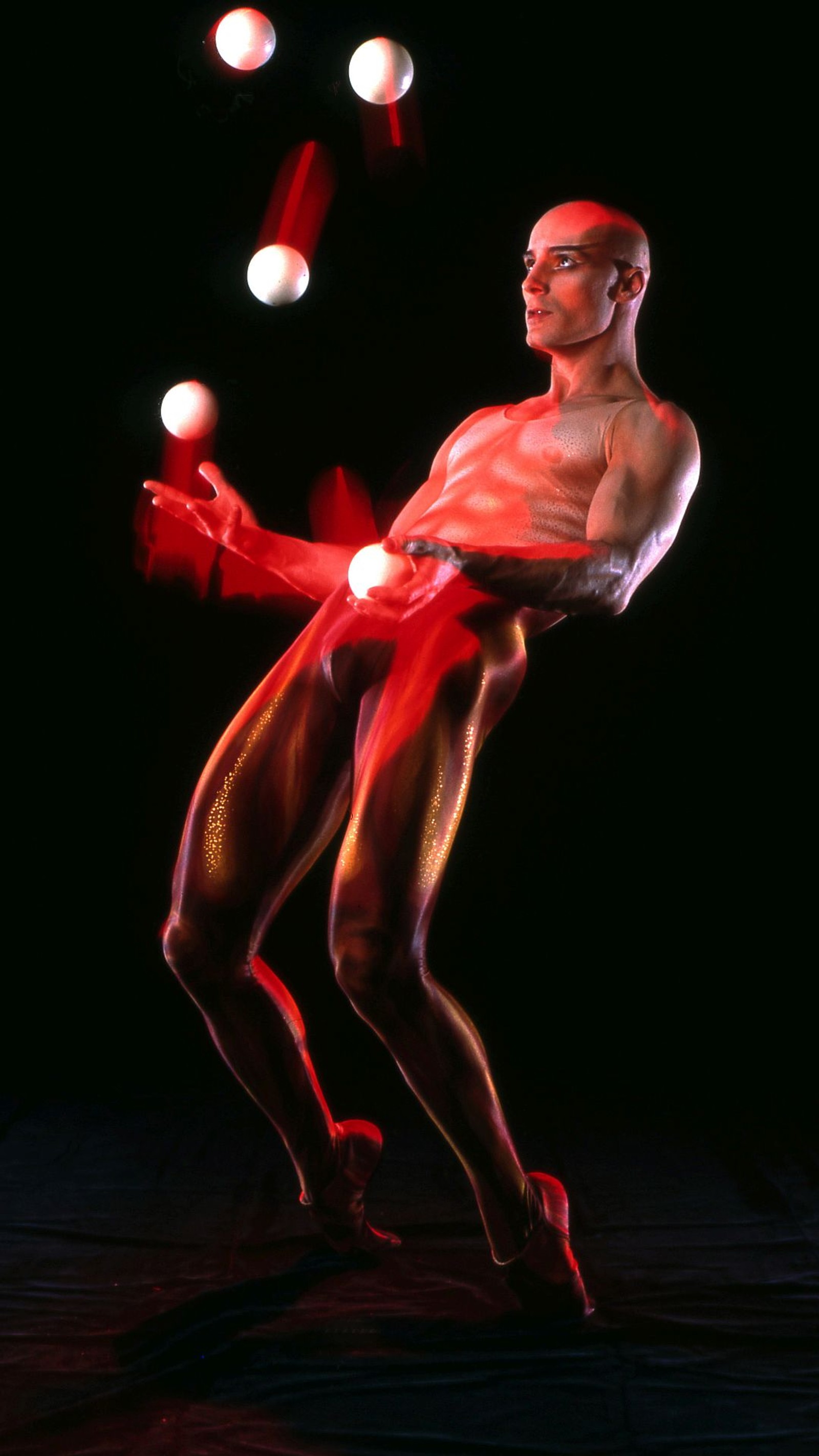 Un hombre haciendo malabares con pelotas en una habitación oscura (americas got talent, juggler, viktor kee)