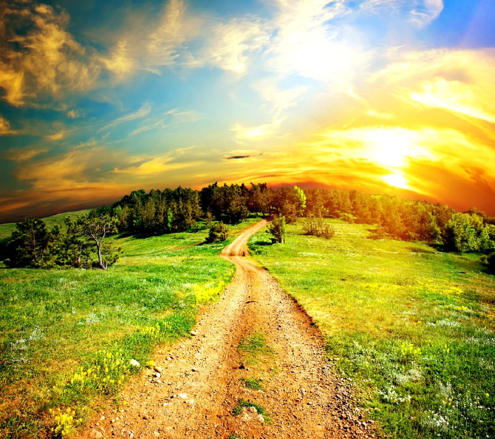 Uma estrada de terra passando por um campo verde com um pôr do sol ao fundo (natureza)