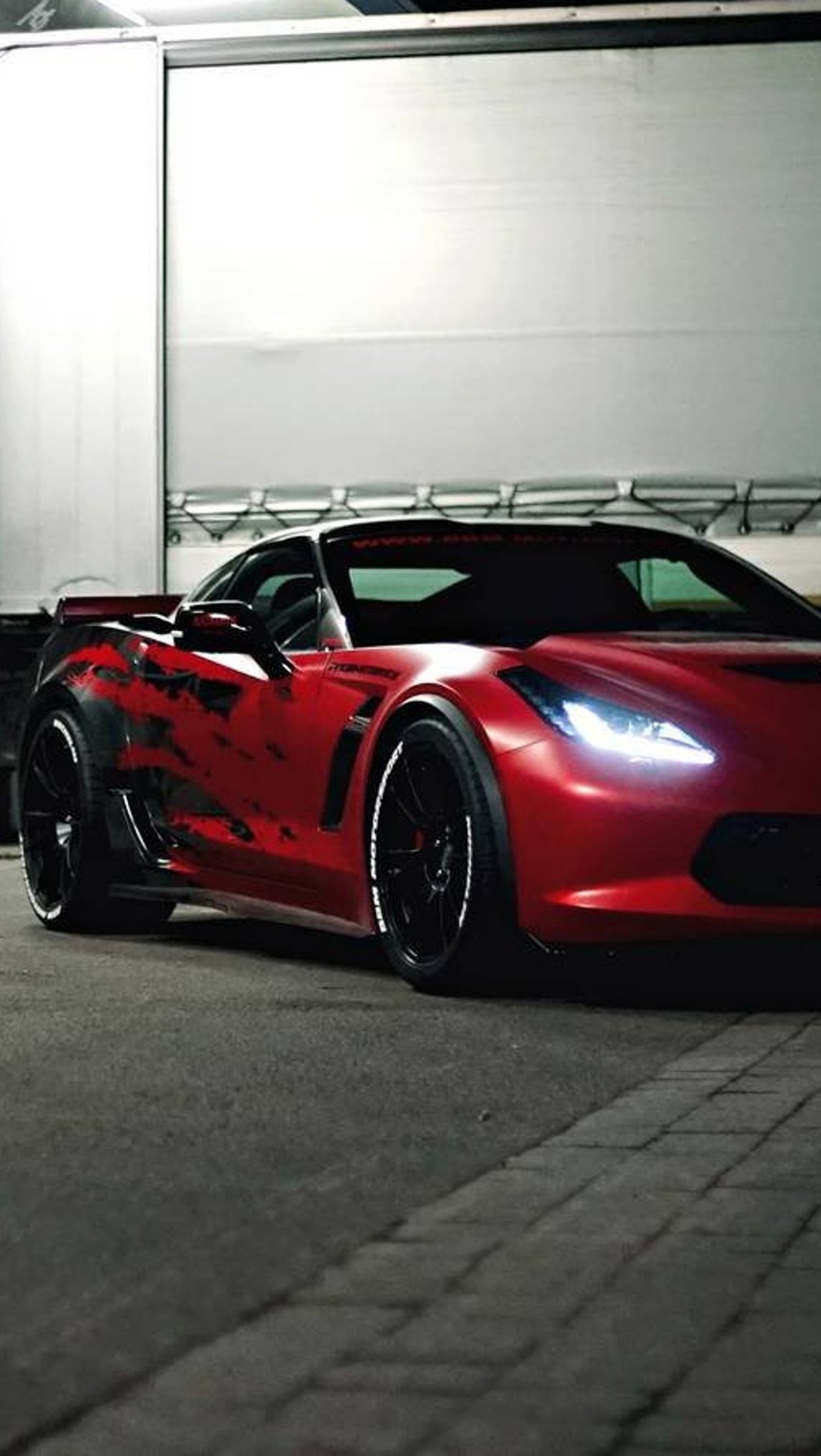 Arafed red sports car parked in a garage with a white trailer (black, car, corvette, red)