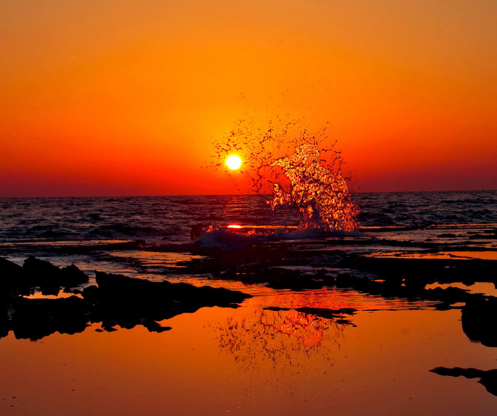 Sunset on the beach with a boat in the water and a splash of water (beach, india, ocean, splash, sunset)