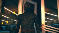 Ezekiel Sims in einem eleganten schwarzen Anzug mit Spinnennetzmustern, posiert am Eingang einer schwach beleuchteten Umgebung im Madame Web-Film.