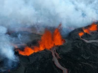 Fonte de lava em erupção em meio a uma paisagem vulcânica fumegante, mostrando as forças dinâmicas da natureza.