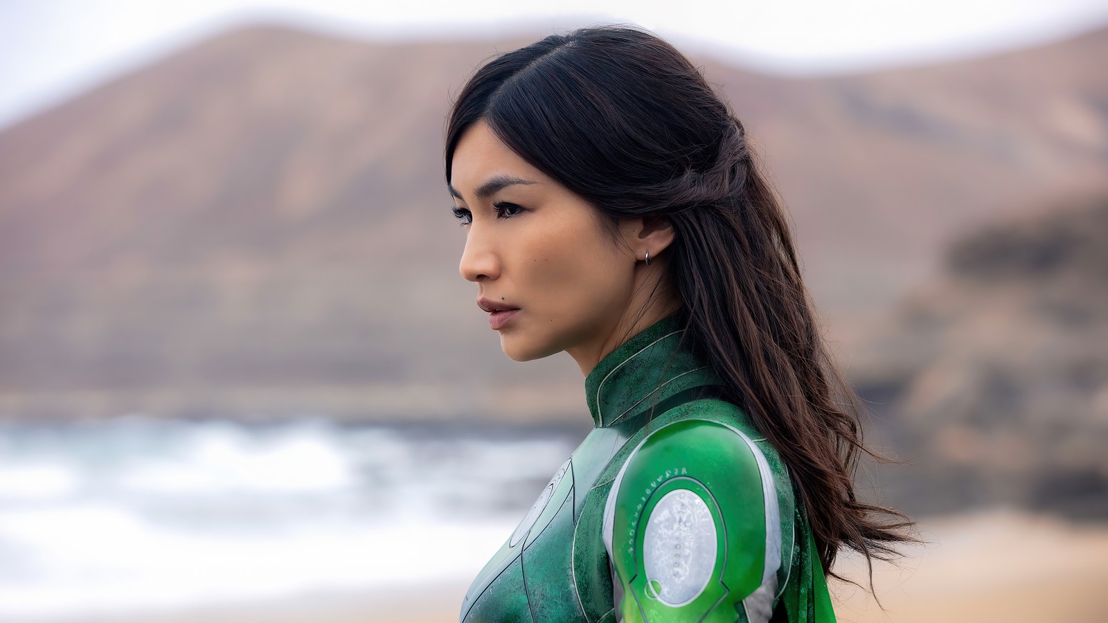 Femme arabe en combinaison verte debout sur une plage (film les éternels, 2021, film, sersi, gemma chan)