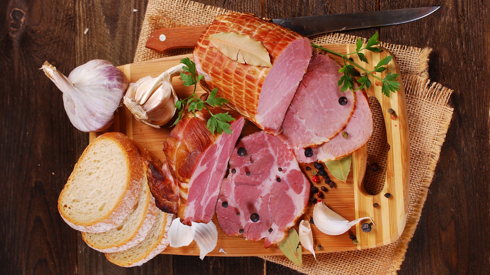 A close up of a cutting board with meat and bread (food, ham, charcuterie, garlic, bread)