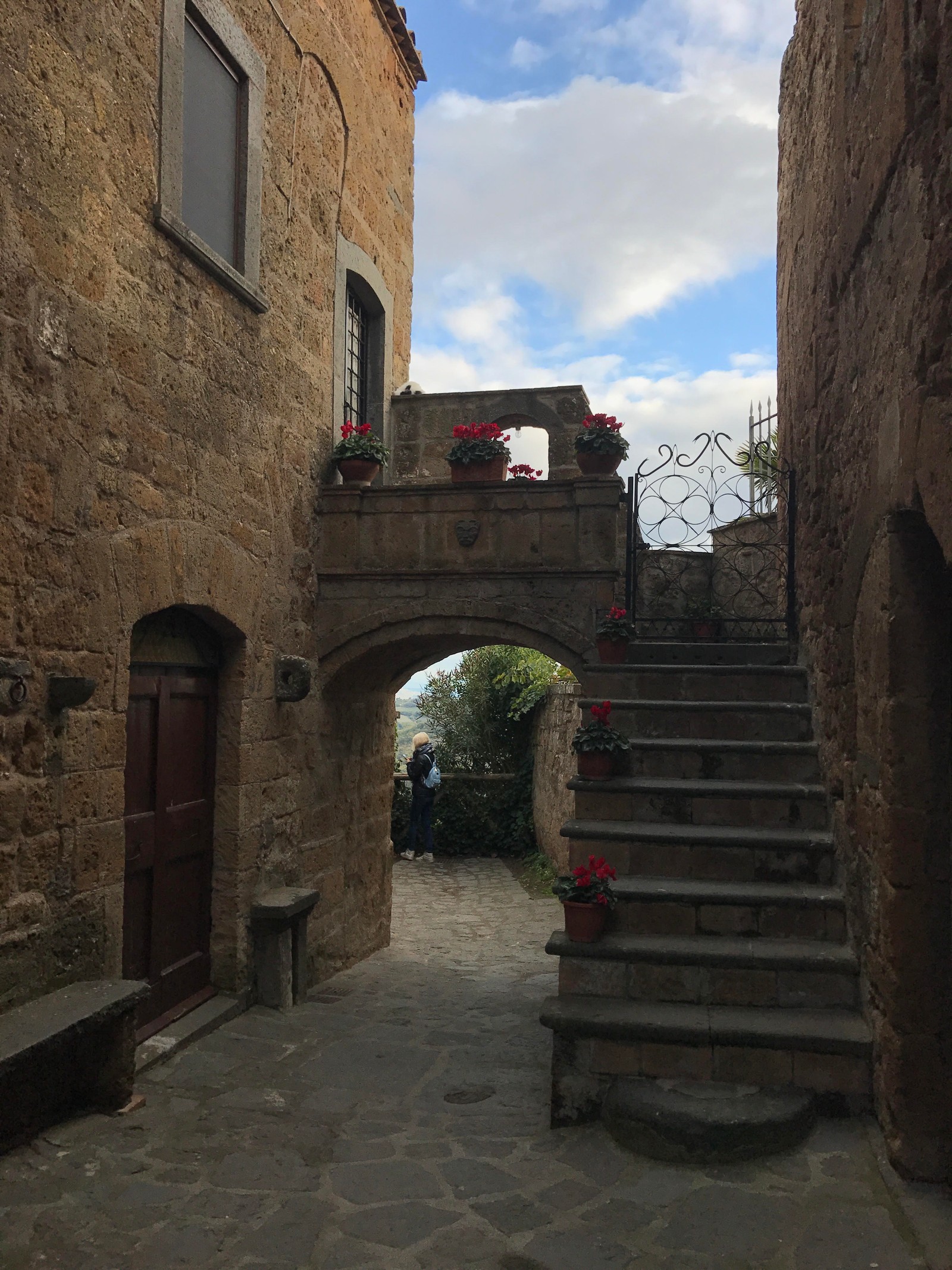 Una escalera de piedra que lleva a un edificio con un arco de piedra (arco, calle, edificio, pared, historia antigua)