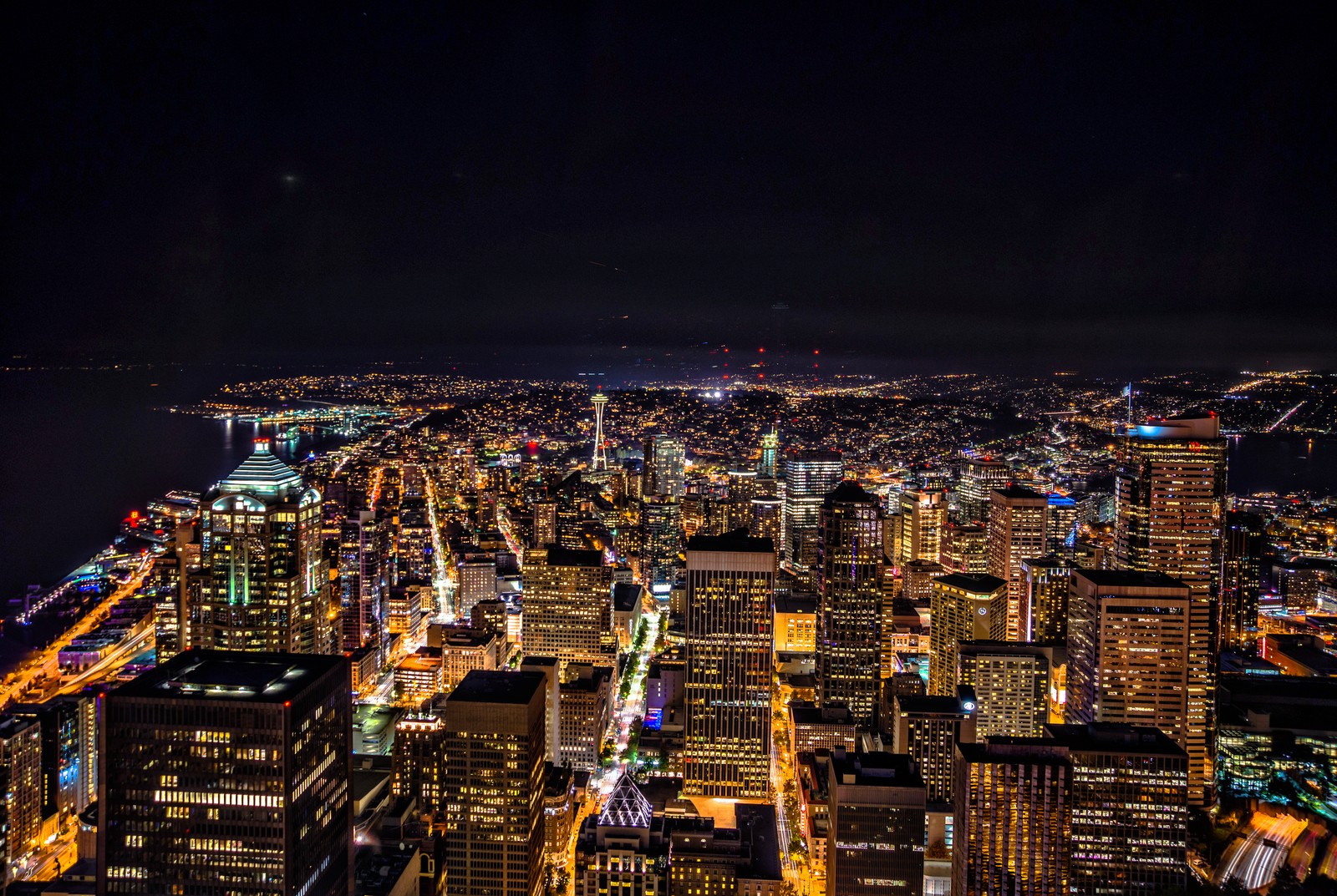 Uma vista de uma cidade à noite com muitas luzes (cidade, arranha céus, seattle, paisagem urbana, noite)