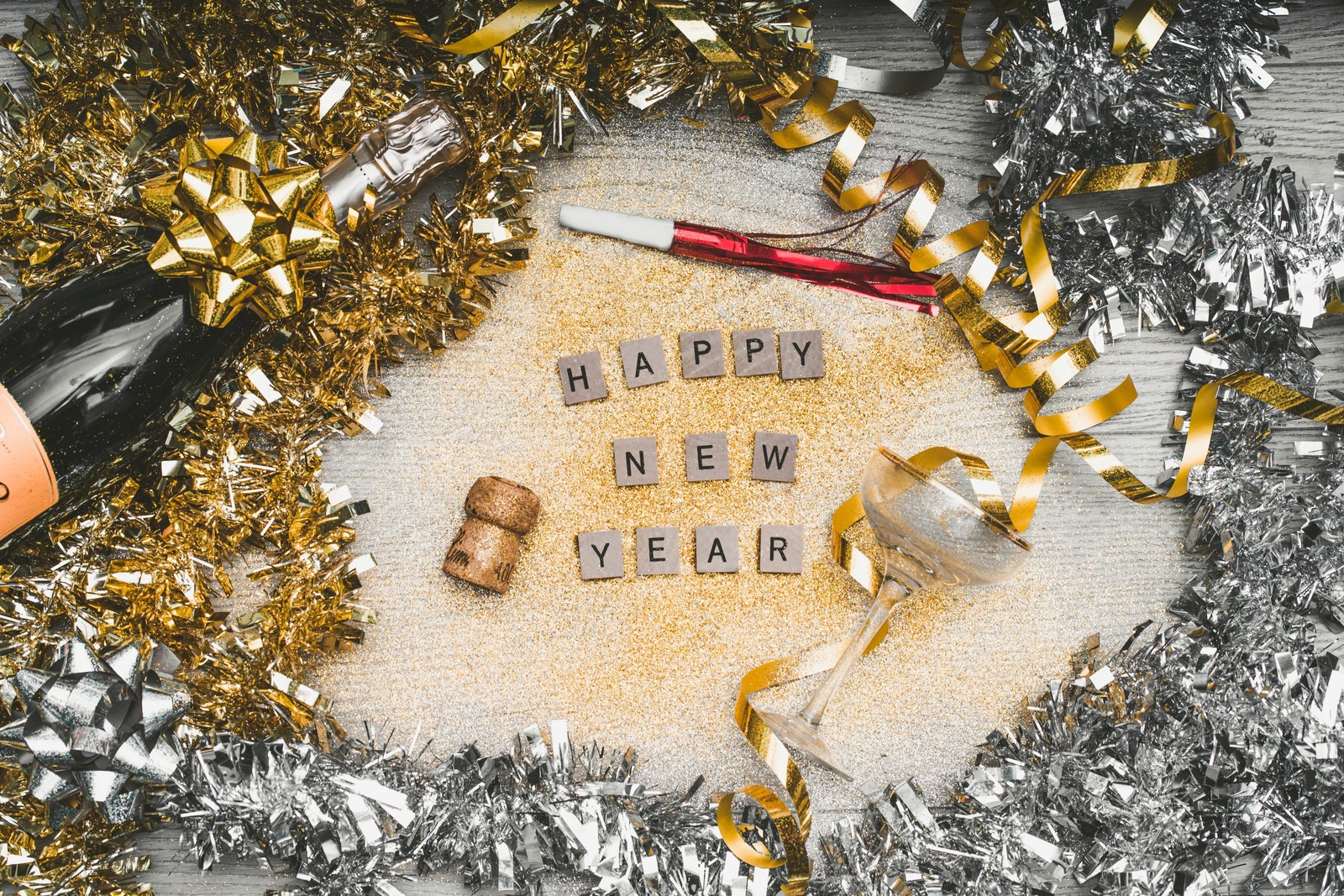 A bottle of champagne and a cork corks with the words happy new year spelled in it (new years eve, new year, christmas day, new years day, holiday)