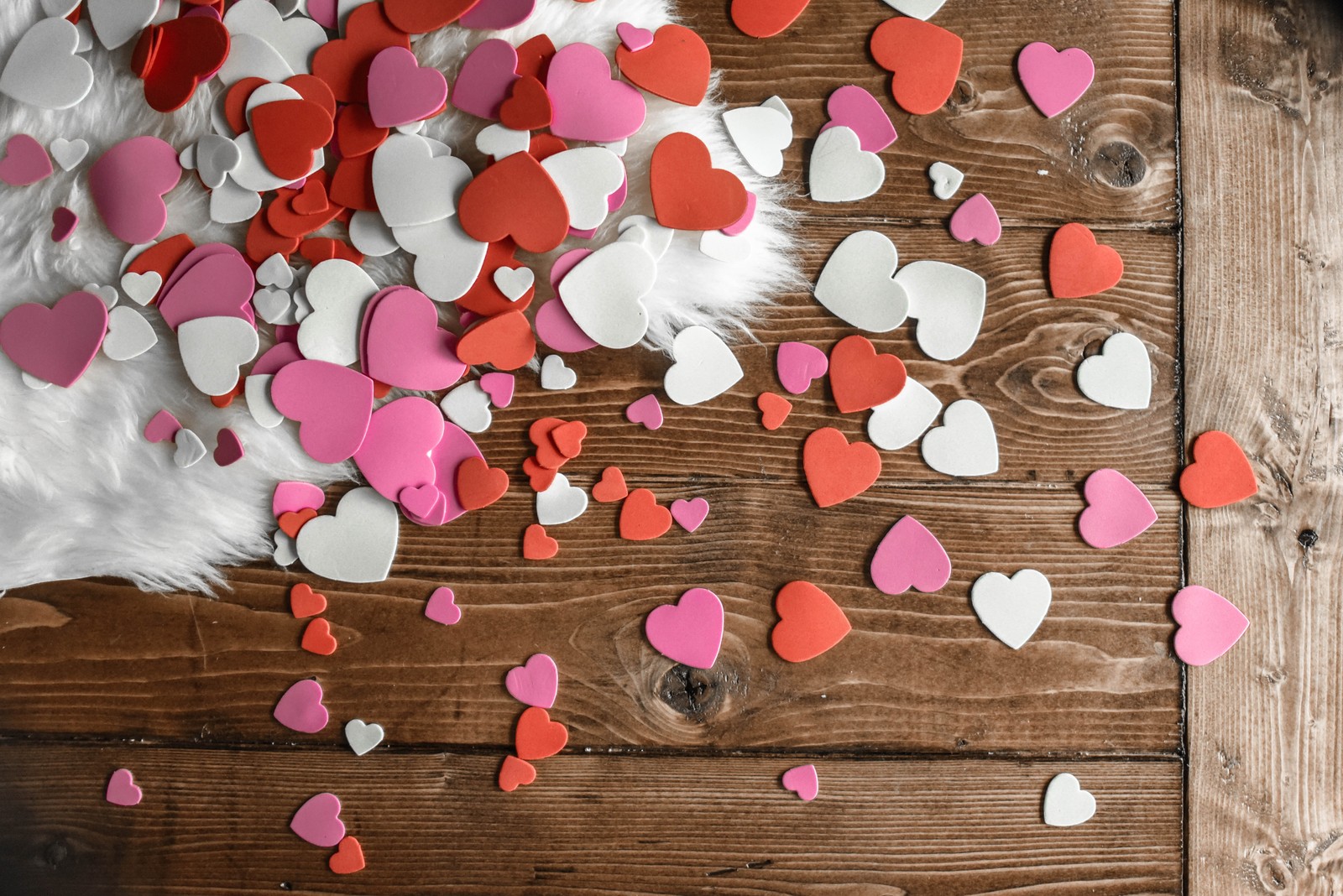 Gros plan d'une pile de cœurs sur une table en bois (saint valentin, cadeau, cœur, rose, pétale)