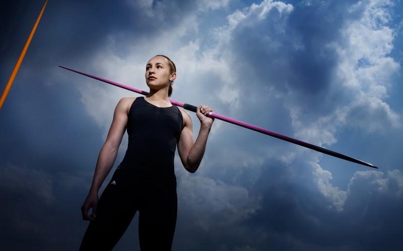 Photo arafed d'une femme tenant un poteau dans le ciel (athlète, nuage, debout, muscle, sauter)