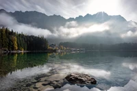 Paisagem alpina serena com reflexos e montanhas nebulosas