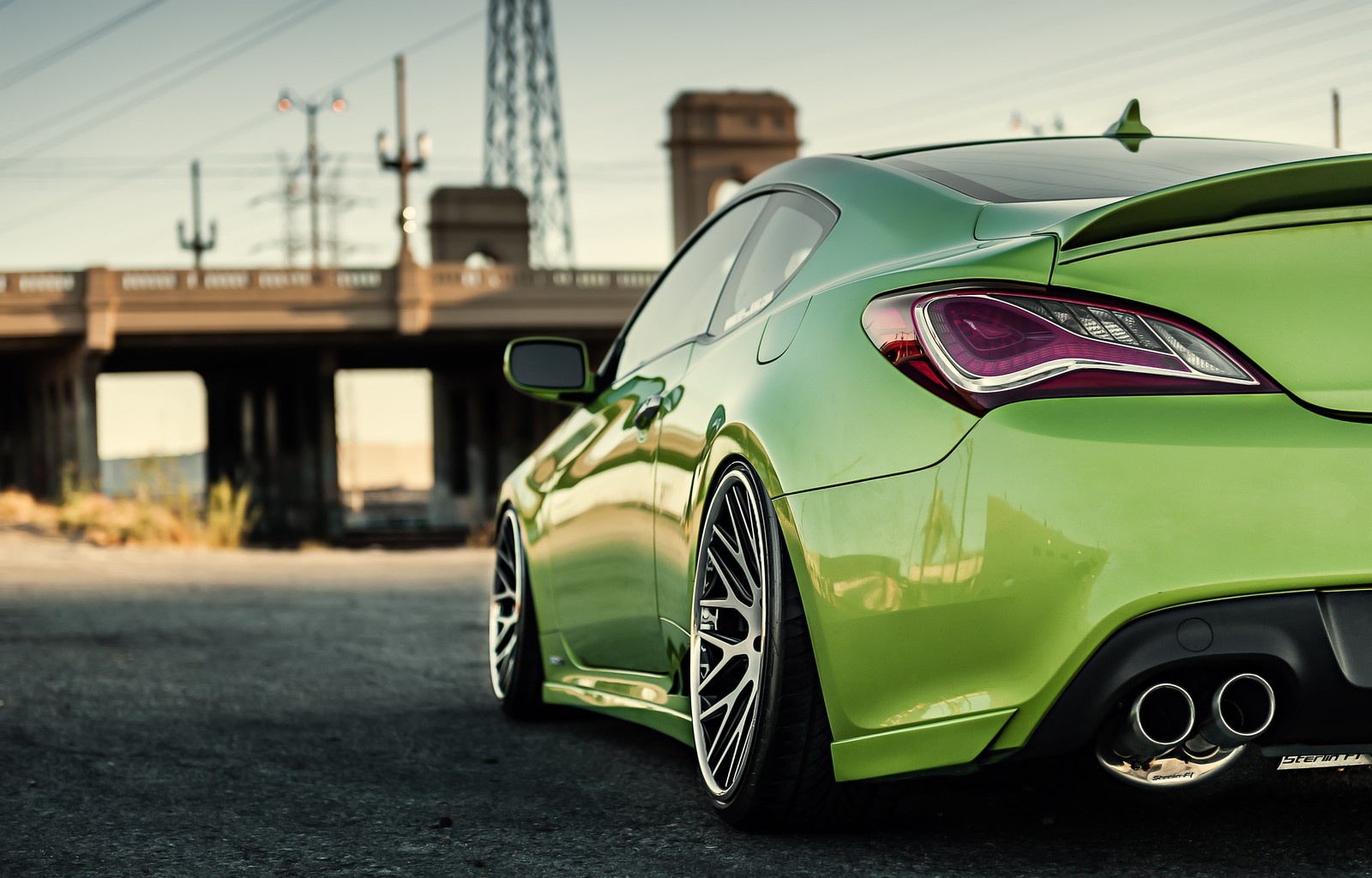 A close up of a green sports car parked on a street (car, sports car, genesis, coup, rim)