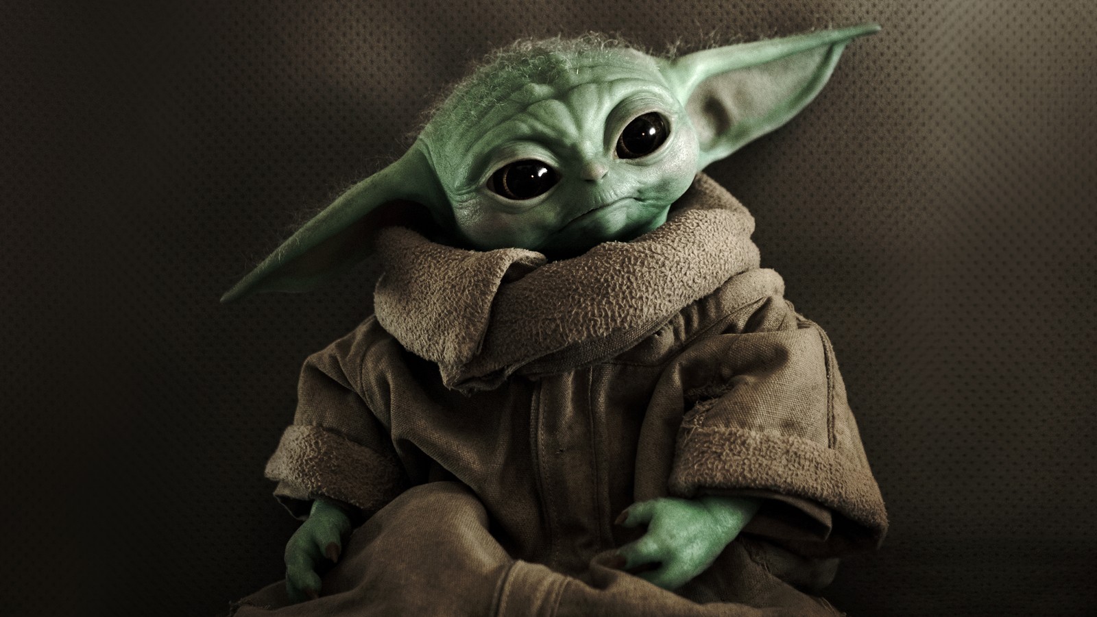 Un primer plano de un bebé yoda con una chaqueta marrón (grogu, bebé yoda, baby yoda, el mandaloriano, temporada 3)