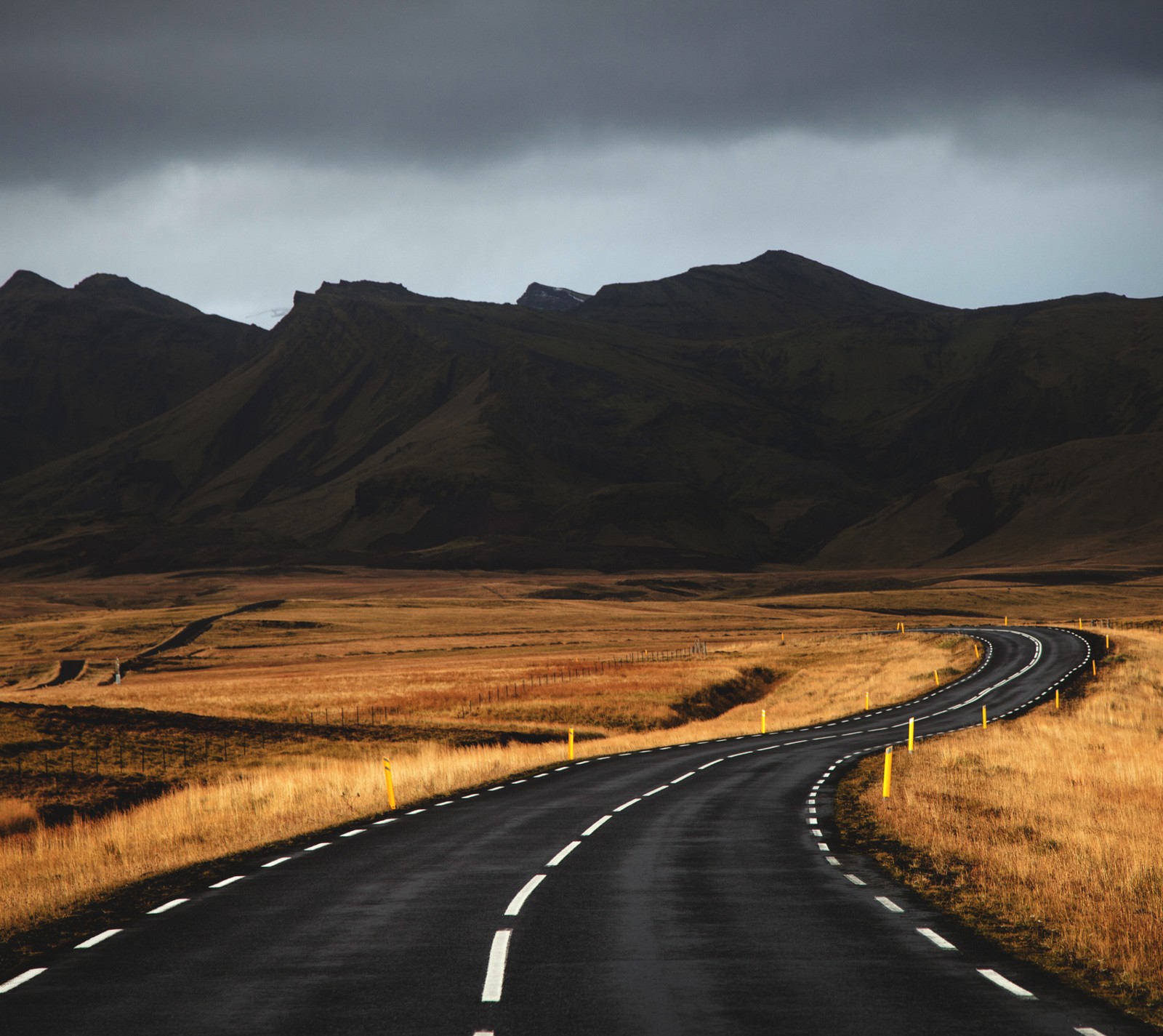 Une route arabe au milieu d'un champ avec des montagnes en arrière-plan (islande, montagnes, route)