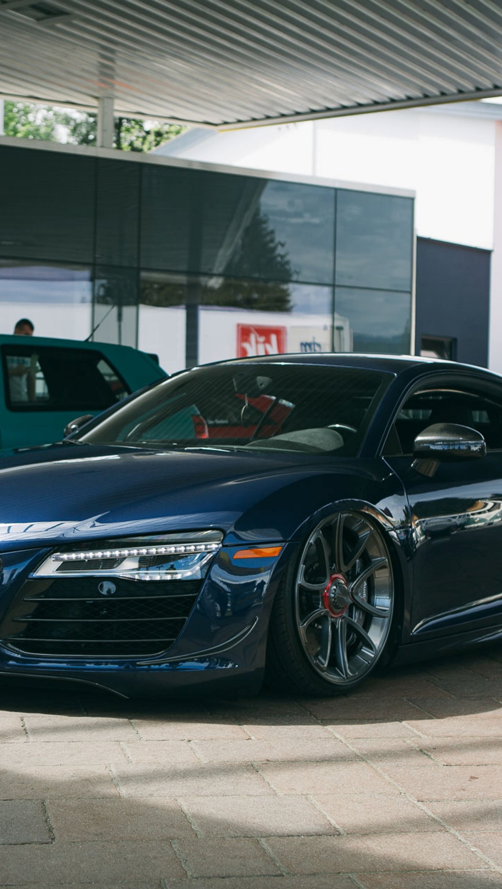 Um carro esportivo azul estacionado em um estacionamento ao lado de um prédio (audi, carro, estrada, super)