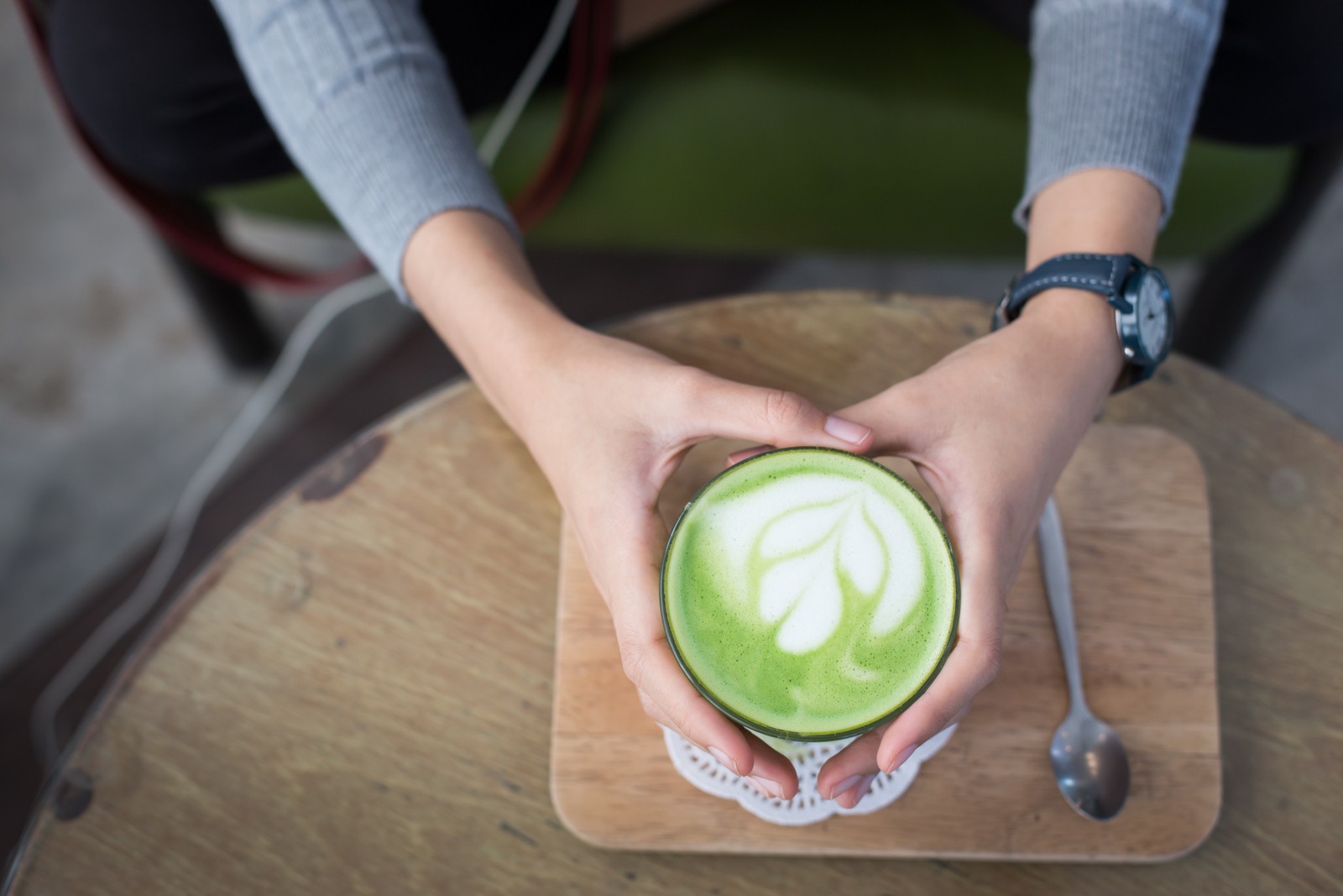 Alguém segurando uma xícara de chá verde com um design de folha (latte, chá verde, chá, café, verde)