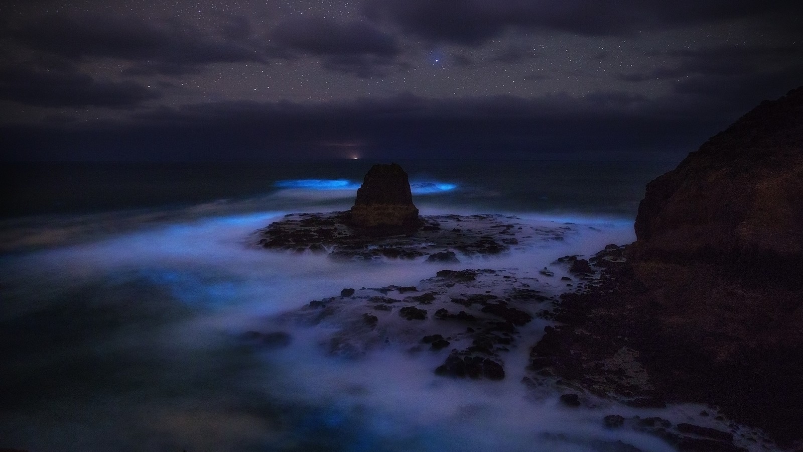 Uma vista de uma praia rochosa com um farol à noite. (natureza, atmosfera, líquido, escuridão, mundo)