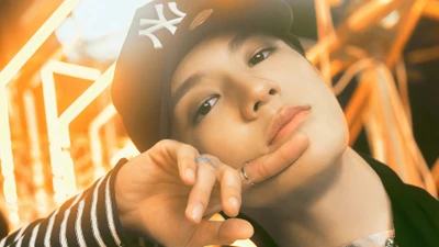 Jeno von NCT U in einer auffälligen Nahaufnahme, die eine selbstbewusste Pose mit einem verspielten Ausdruck zeigt, umgeben von dynamischem Licht.