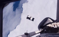 Space Shuttle Discovery with Satellite Above Snow-Covered Earth and Clouds