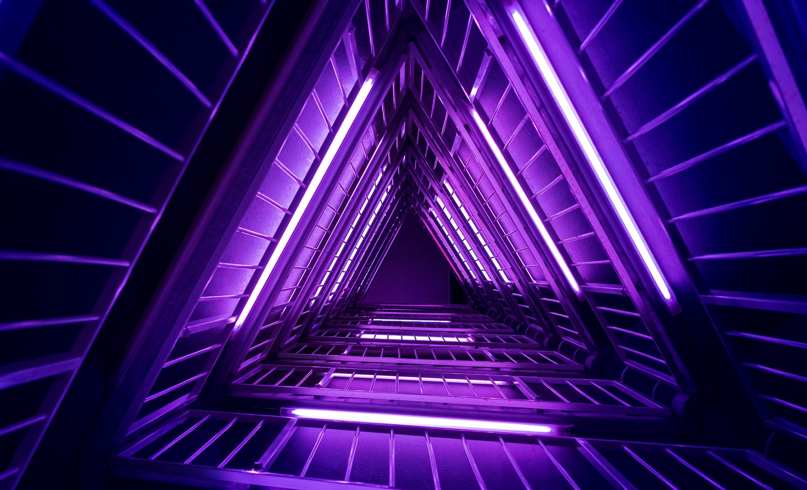 Eine nahaufnahme einer treppe mit lila lichtern in einem gebäude (neon dreieck, lila licht, fotografie aus niedriger perspektive, nach oben schauen, geometrisch)