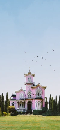 Charmante maison victorienne rose entourée de verdure luxuriante et d'oiseaux en vol