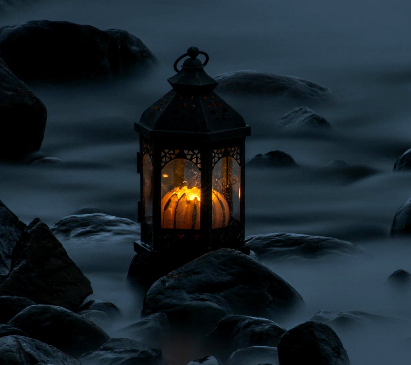 There is a lantern that is lit up on the rocks (lantern, misty)