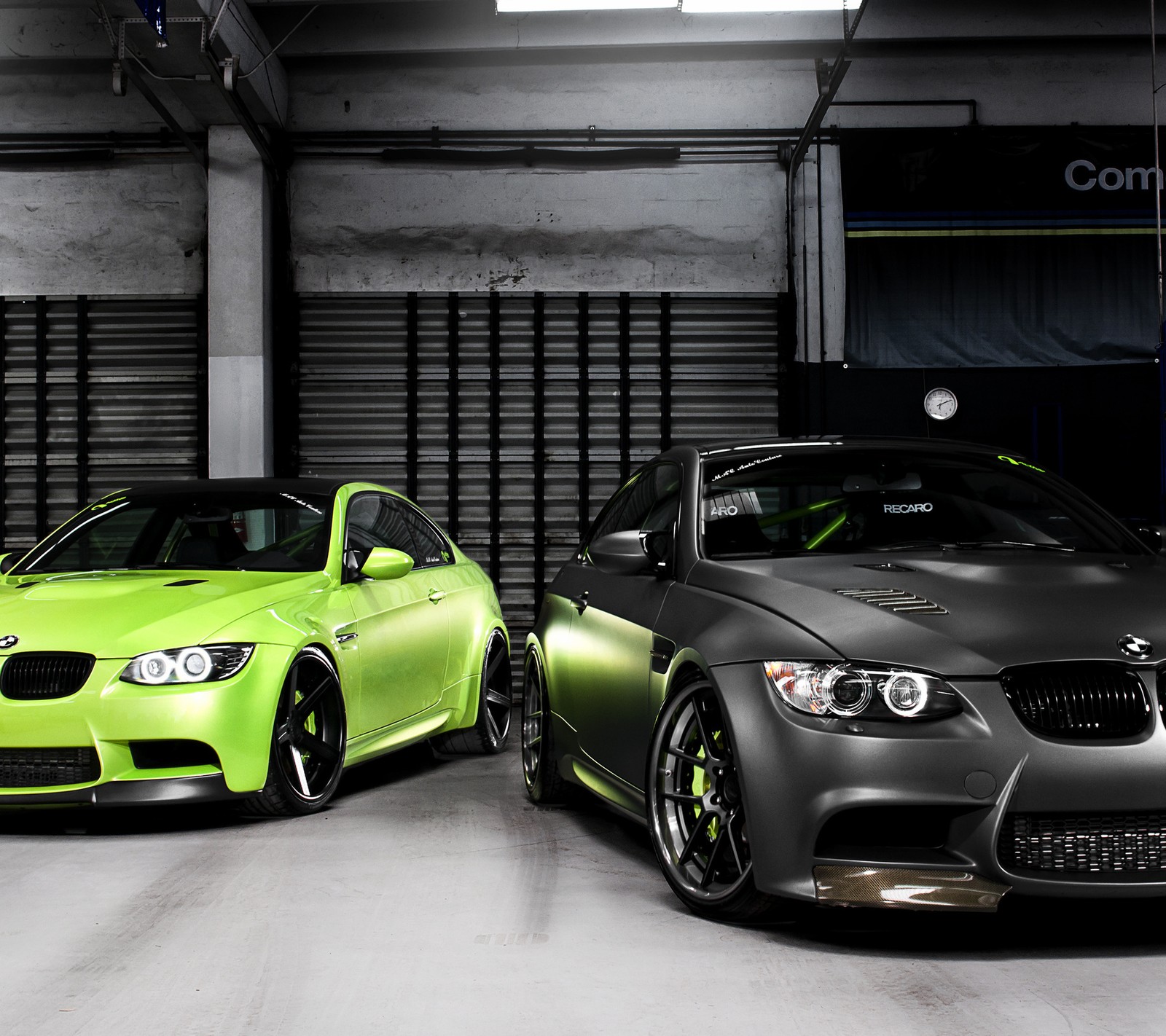 Two cars are parked in a garage with a garage door open (autos, cars)