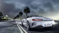 Sleek Mercedes-Benz AMG GT on a moonlit coastal road, showcasing luxury and performance.